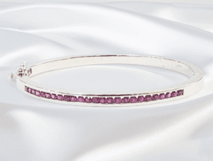 Silver bracelet with purple gemstones on fabric.